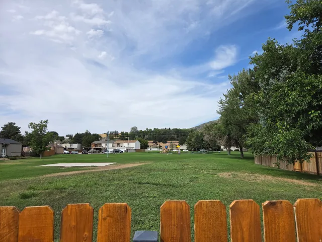 Private yard with wood fencing bordering a large green space
