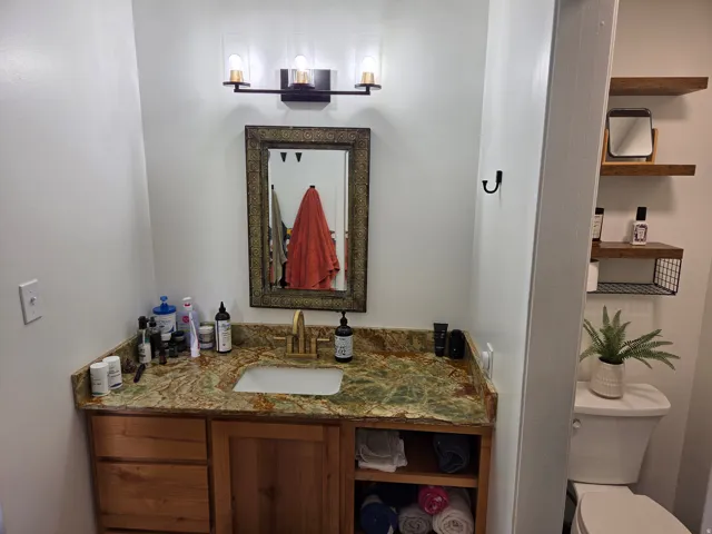 Custom vanity with wood-finish cabinetry, green-veined countertop, and an undermount sink