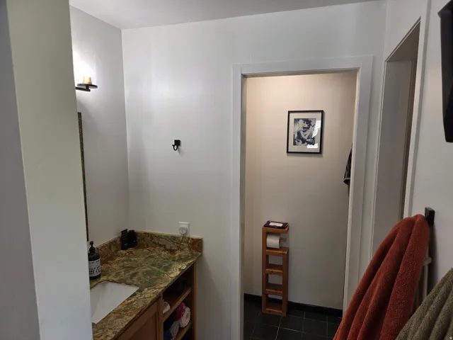 Built-in vanity with a stone countertop, undermount sink, and open shelving
