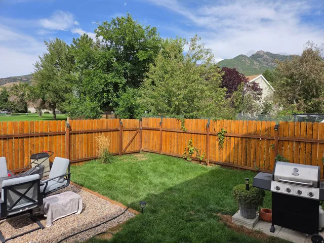 Fenced backyard featuring a gravel patio area and a manicured lawn