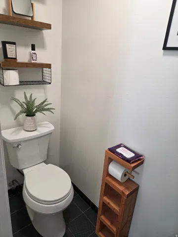 White toilet with dark tile flooring
