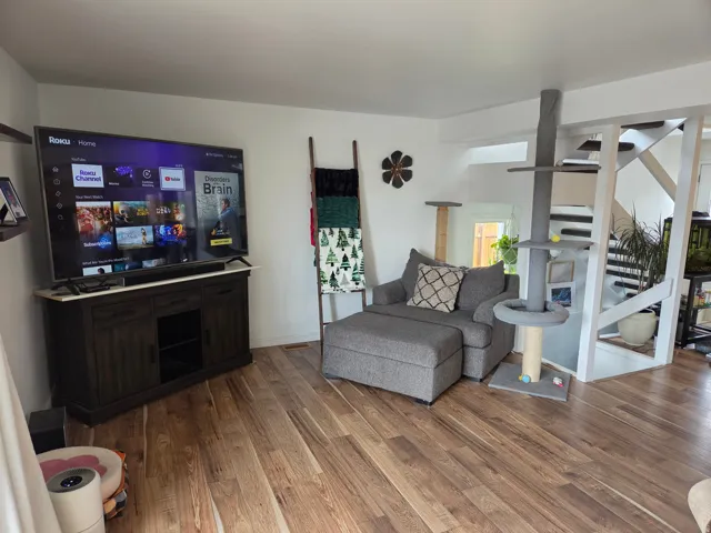 Wood-finish flooring throughout, white walls, and an open staircase with white risers