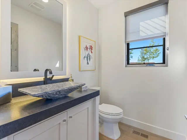 Vanity with an integral vessel sink, a matte black faucet, and under-cabinet lighting