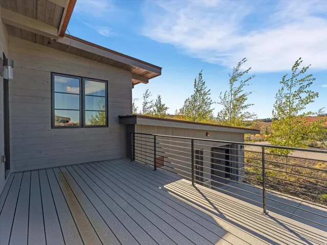 Outdoor deck featuring composite decking, black metal railings, and natural wood soffits