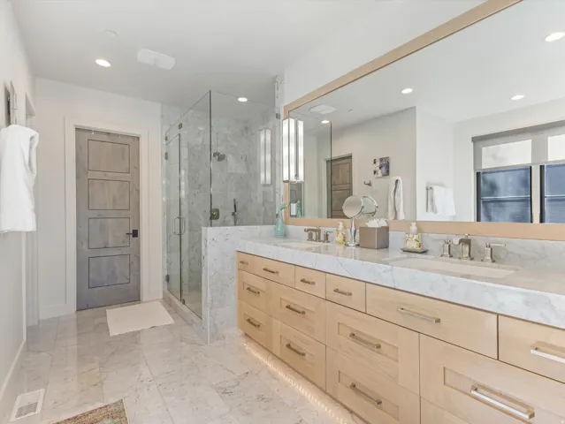 Dual vanity with light wood finish cabinetry and stone countertop