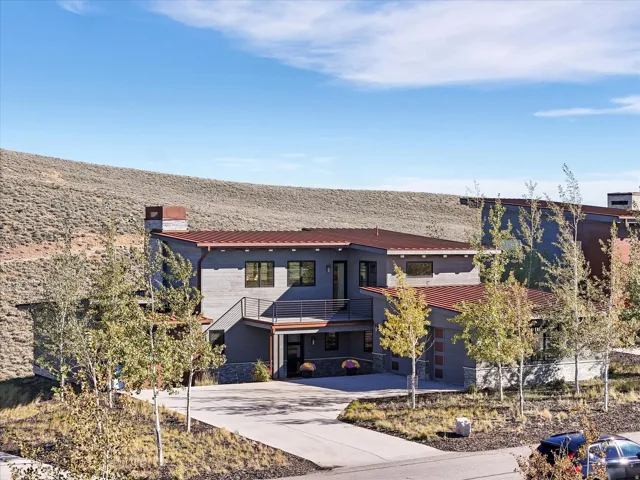 Contemporary exterior with multiple rooflines, a metal roof, an integrated garage, and a balcony with metal railings