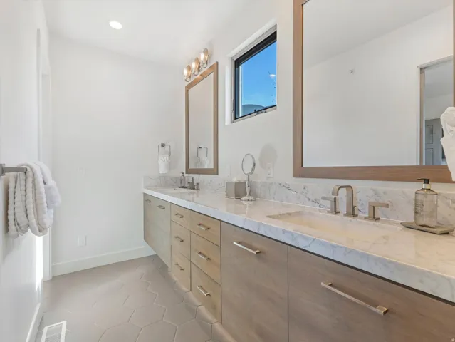 Floating dual vanity with wood-finish cabinetry, integrated sinks, and brushed nickel fixtures