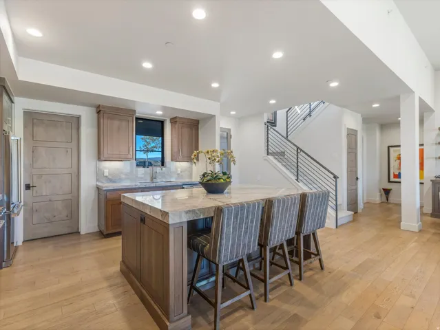 Hardwood flooring throughout, recessed lighting, and a kitchen island with a stone countertop