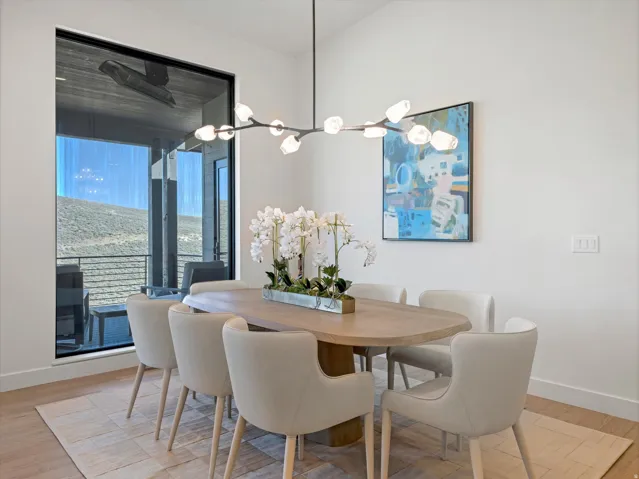 Expansive window offering mountain scenery, vaulted ceiling, and wood-finish flooring