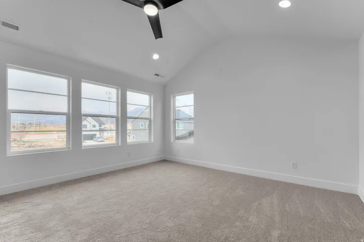 Vaulted ceiling with a ceiling fan, recessed lighting, expansive windows, and light-toned carpeting