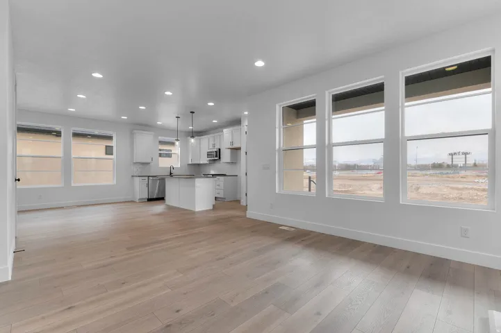 Open-concept living space featuring wood-finish flooring, recessed lighting, and expansive windows