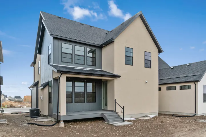 Contemporary exterior with a covered porch, dark gray siding, light-toned stucco, and multiple black-framed windows