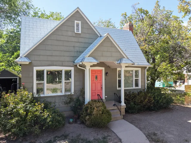 Gable roof with shingle siding, covered entry with columns, exterior steps with railings, and a detached garage