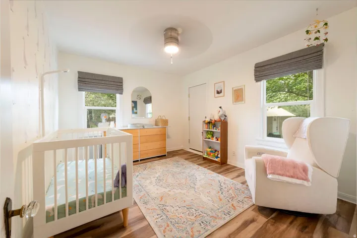 Wood-finish flooring, white walls, two windows with blinds, and a ceiling-mounted light fixture