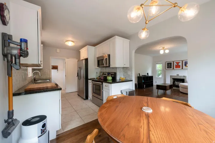 Kitchen featuring white cabinetry, stainless steel appliances, dark countertops, and tile flooring