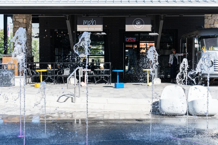 Paved outdoor area featuring multiple water jets and stone elements