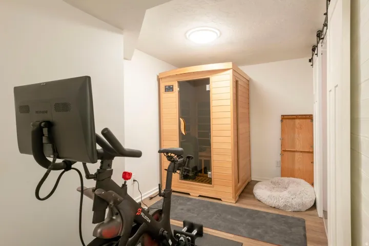 Wood-finish flooring with a light-toned wood sauna featuring a glass door