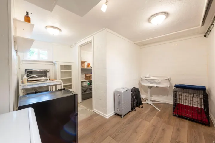 Wood-finish flooring, white painted walls, built-in shelving, recessed ceiling lighting, and a window providing natural light