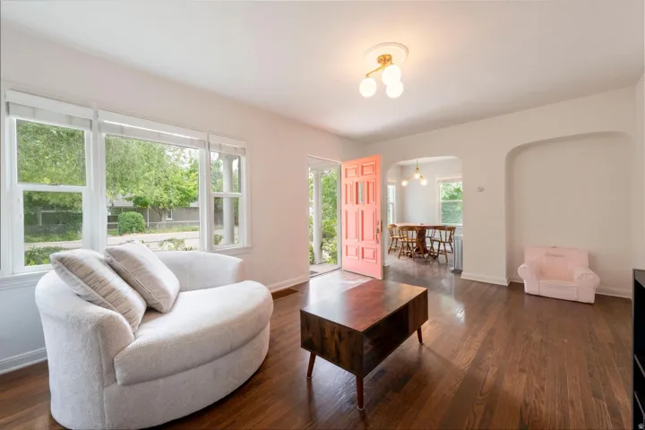Wood-finish flooring throughout, multiple windows, archway, decorative ceiling light fixture, and a paneled front door