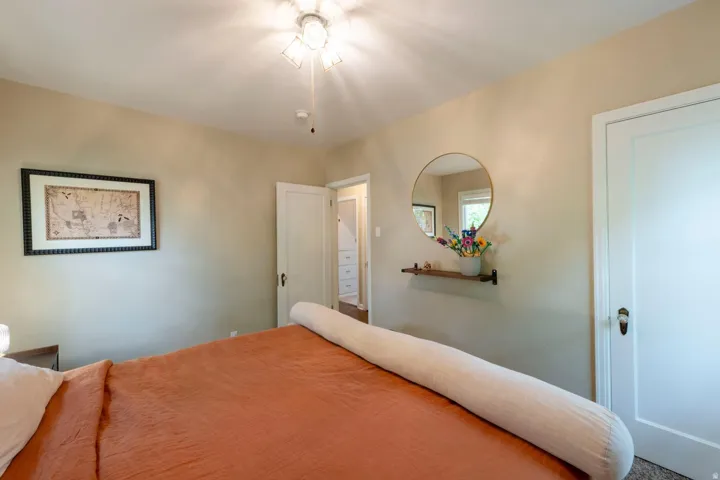 Ceiling-mounted light fixture, built-in shelving, and a round wall mirror
