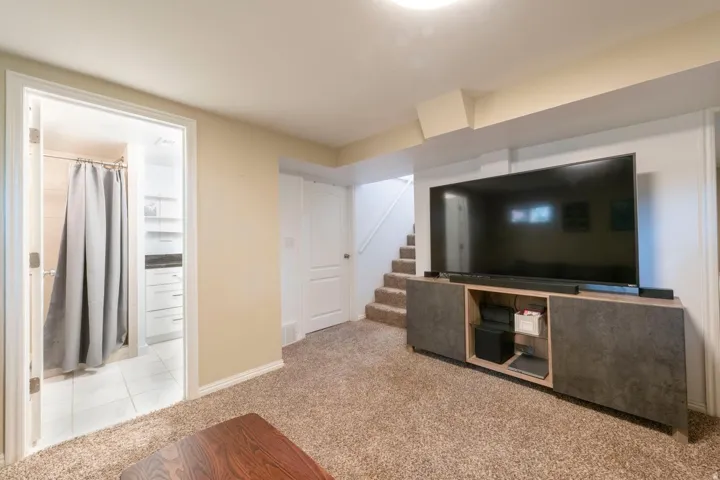 Carpeted flooring, a staircase with carpeted treads, and a built-in media console