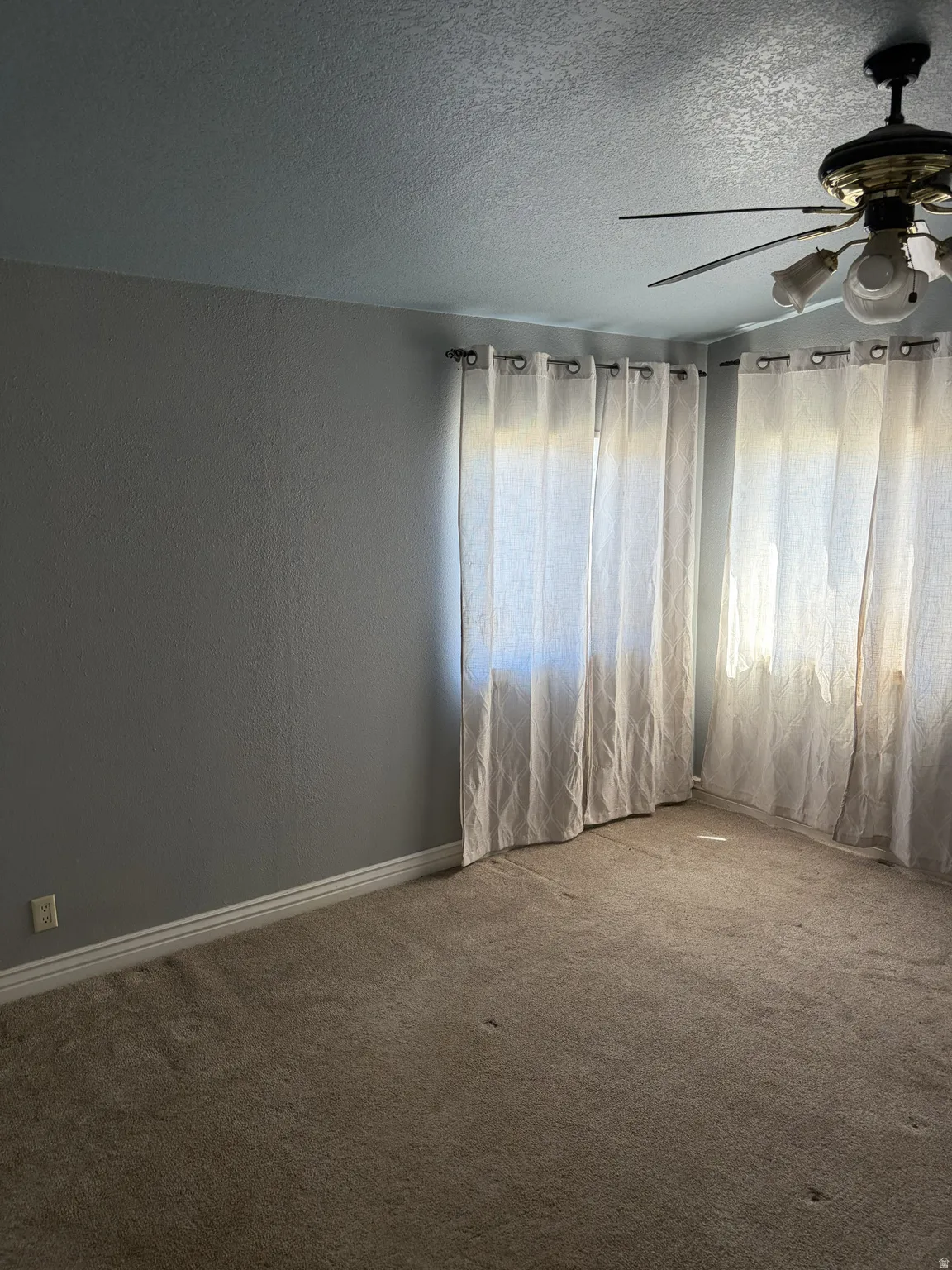 Textured walls, ceiling fan with integrated lighting, and carpeted flooring