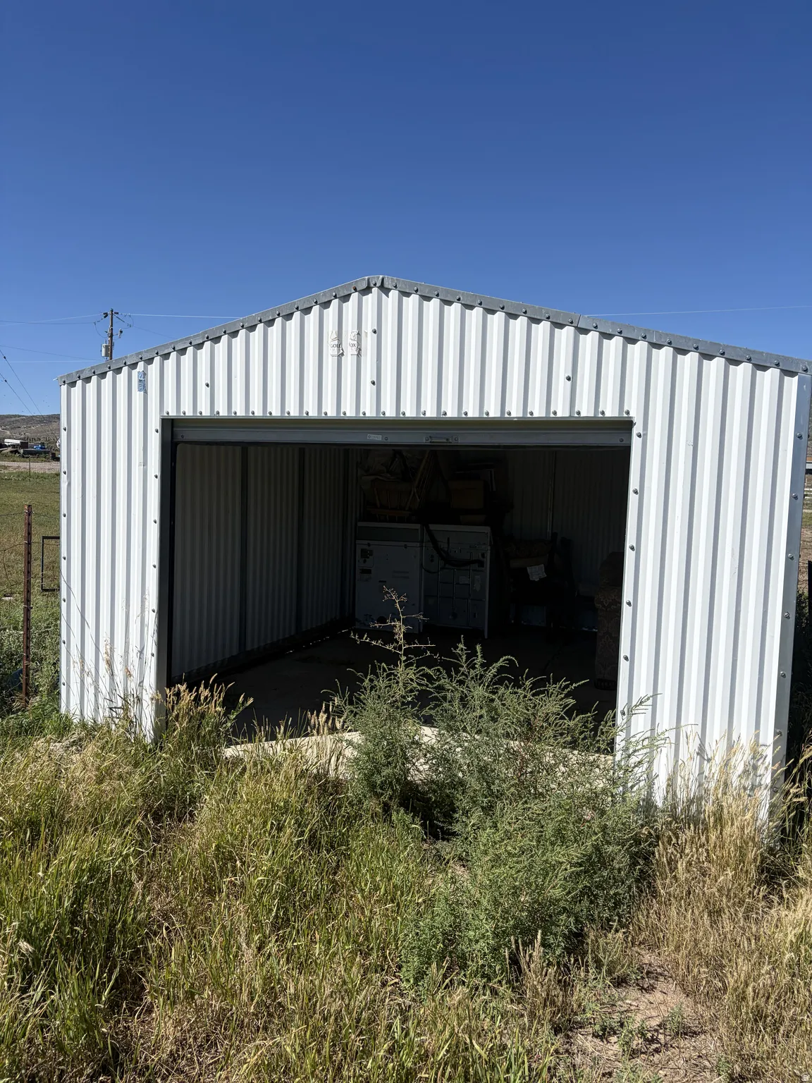 Corrugated metal storage shed with a gable roof and open entry