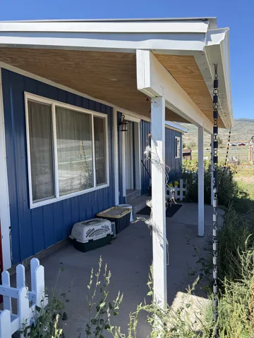 Covered concrete porch with white support columns, blue horizontal siding, and a white picket fence