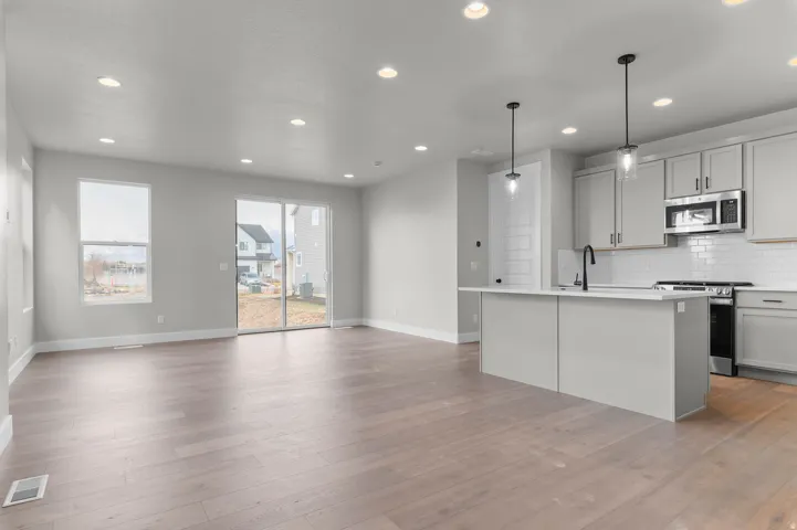 Wood-finish flooring, recessed lighting, and a kitchen island with pendant lighting