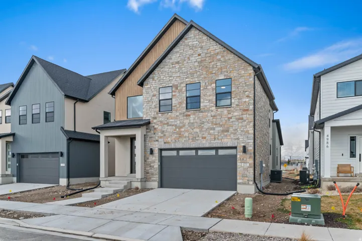 Modern exterior featuring stone veneer, vertical siding, and a covered entry