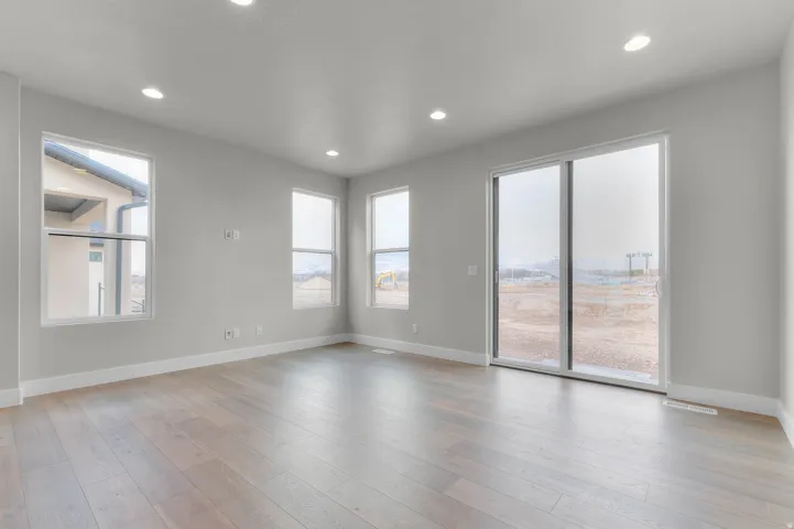 Light wood-finish flooring, recessed ceiling lighting, multiple windows, and a sliding glass door