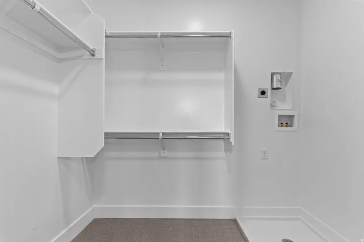 Dedicated utility area featuring white walls, built-in shelving, hanging rods, and a utility sink base