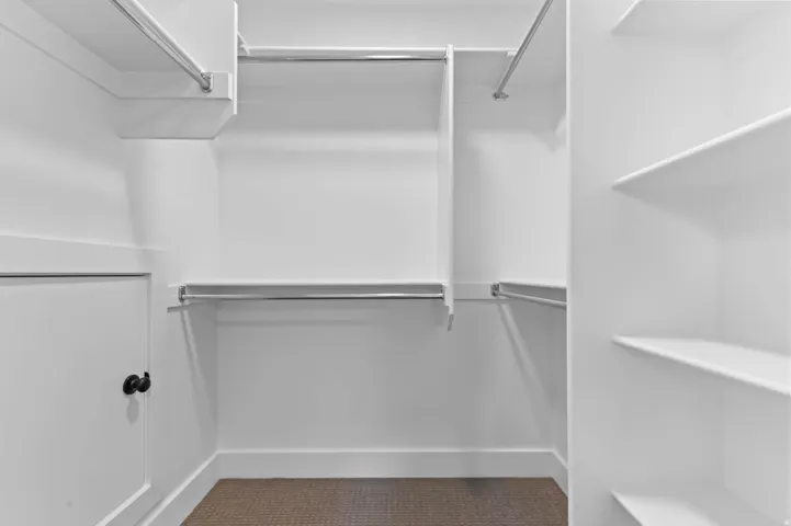 White built-in shelving, multiple hanging rods, and carpeted flooring