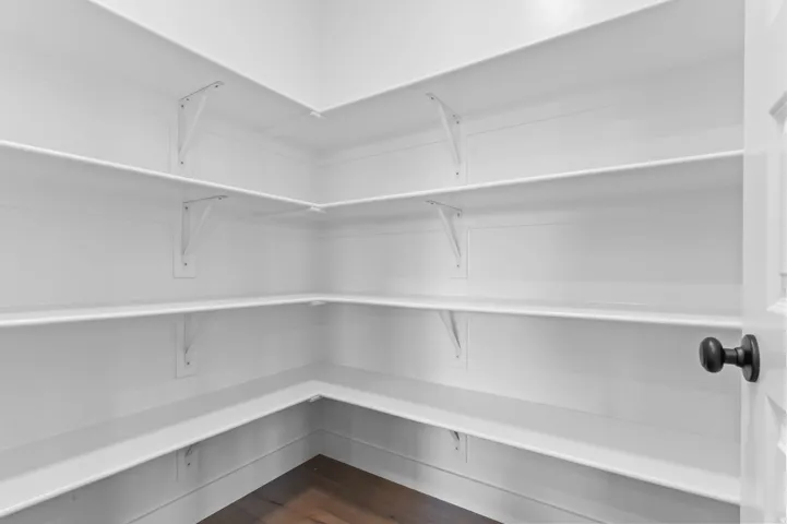 White shelving, dark wood-finish flooring, and a black doorknob