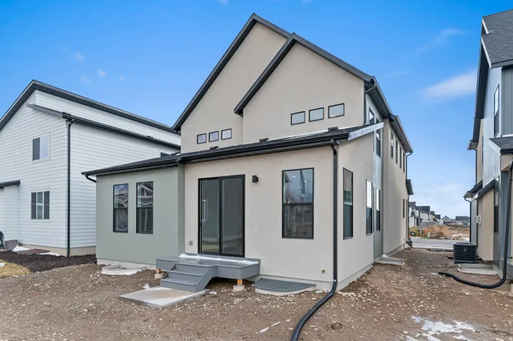 Stucco exterior with black-framed windows, sliding glass door, multi-level deck, and dark-toned gutters