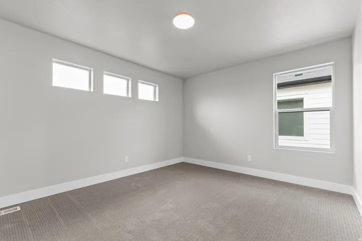 Neutral wall color, recessed lighting, expansive carpeted flooring, multiple windows, and white trim