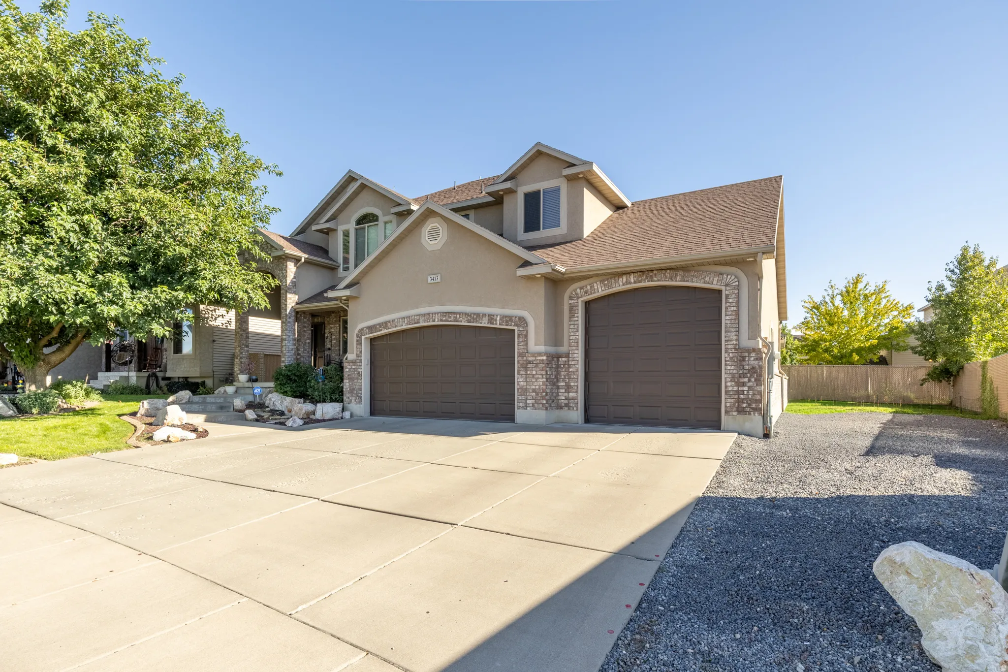 Impressive three-car garage with an extra-deep third bay, wide concrete driveway, and expansive gravel RV parking—offering abundant space for vehicles, trailers, and recreational toys.