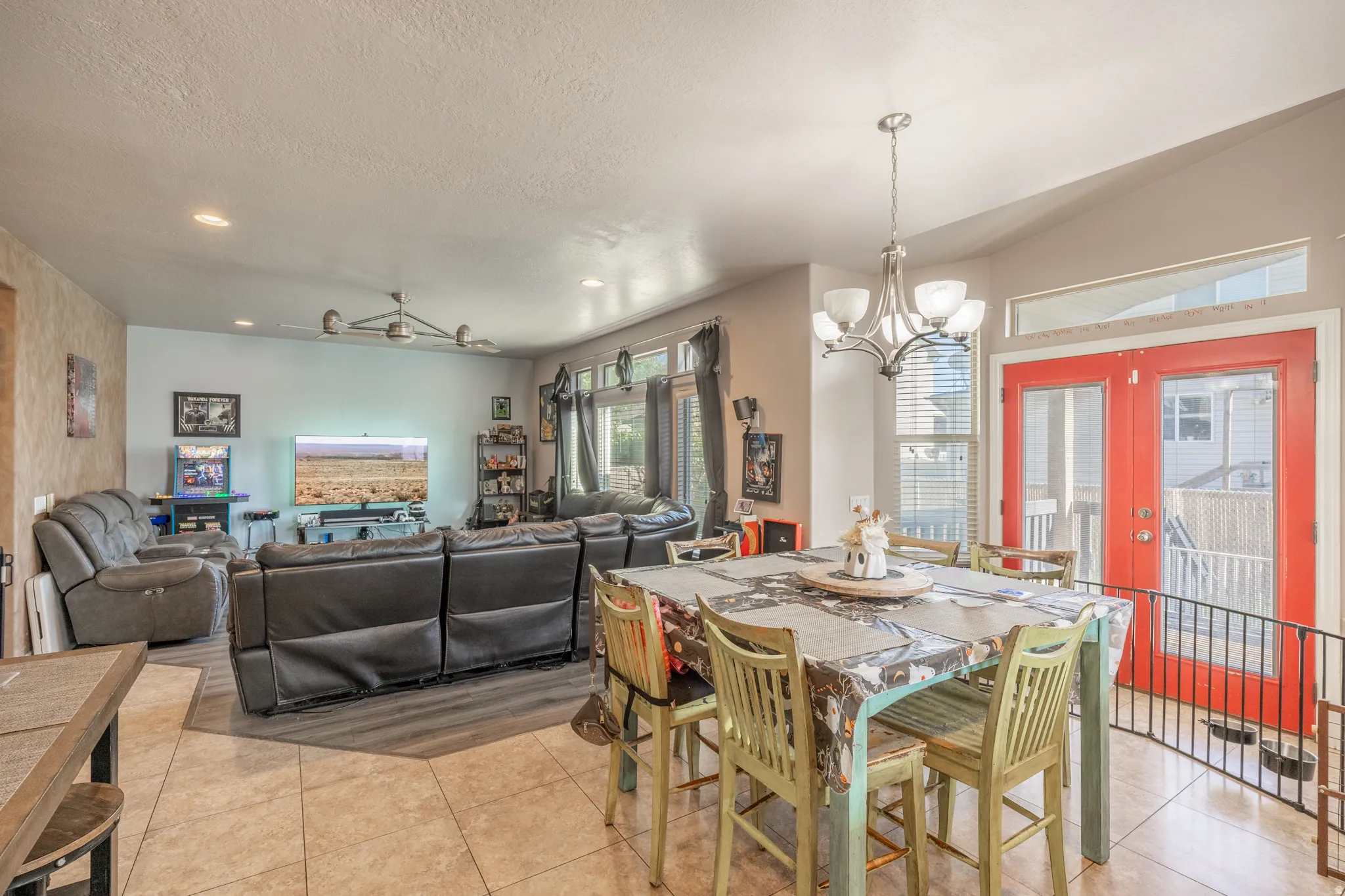 Bright, open-concept dining and living area featuring expansive windows, stylish flooring, and French doors leading to the covered deck—creating a seamless setting for indoor-outdoor entertaining.