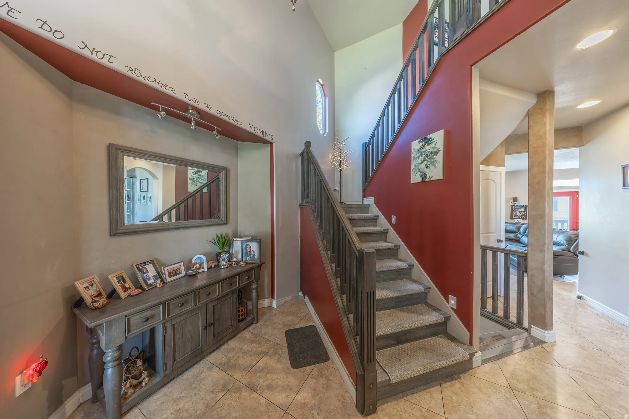 A dramatic, light-filled entry welcomes you with soaring vaulted ceilings, an elegant open staircase enhanced by integrated LED smart lighting, contemporary railings, and durable tile flooring.