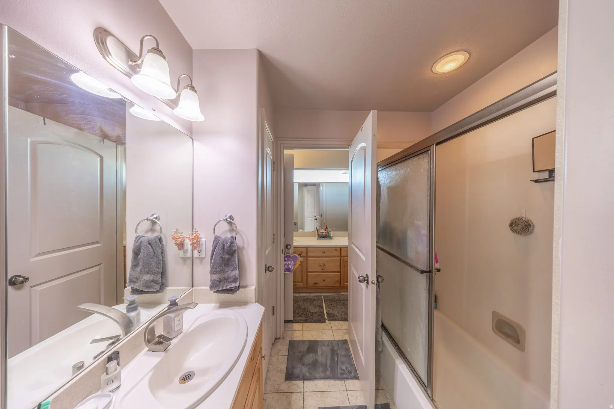 Thoughtfully designed Jack-and-Jill bathroom connecting two second-floor bedrooms, featuring dual vanities, a private toilet area, and a shared tub-and-shower combination for added comfort and convenience.