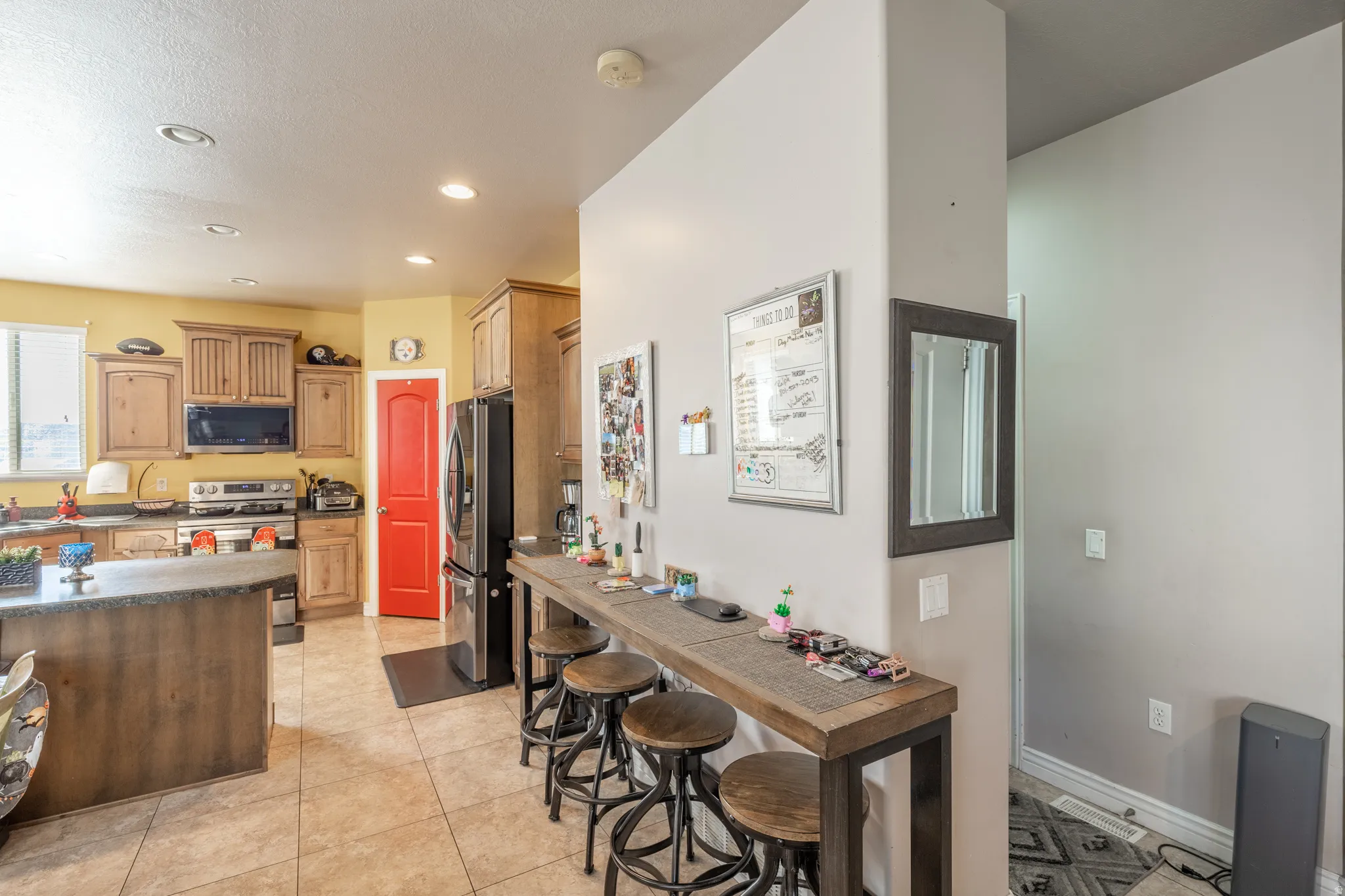 Thoughtfully designed kitchen featuring warm wood cabinetry, stainless-steel appliances, recessed lighting, generous counter space, and additional breakfast-bar seating for casual dining.
