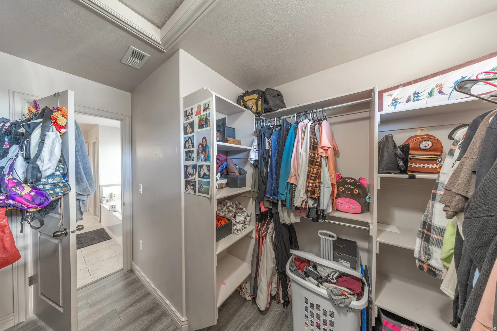 Generously sized primary walk-in closet featuring extensive shelving and hanging space, with convenient direct access to the en-suite bathroom