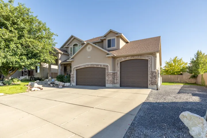 Impressive three-car garage with an extra-deep third bay, wide concrete driveway, and expansive gravel RV parking—offering abundant space for vehicles, trailers, and recreational toys.