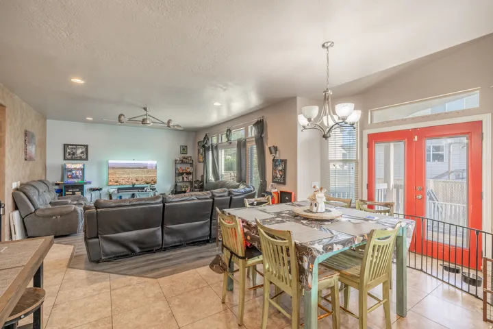 Bright, open-concept dining and living area featuring expansive windows, stylish flooring, and French doors leading to the covered deck—creating a seamless setting for indoor-outdoor entertaining.