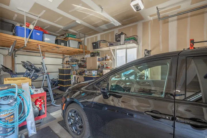 Extra-deep garage bay featuring an EV charging hookup, pull-through rear garage door, overhead storage, and installed workout equipment—offering exceptional flexibility for vehicles, recreation, and additional storage.