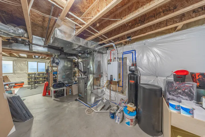 Basement landing and utility area featuring a tankless water heater, water softener, newer dual-furnace system for enhanced year-round temperature control, and convenient interior controls for the home’s exterior lighting outlets.