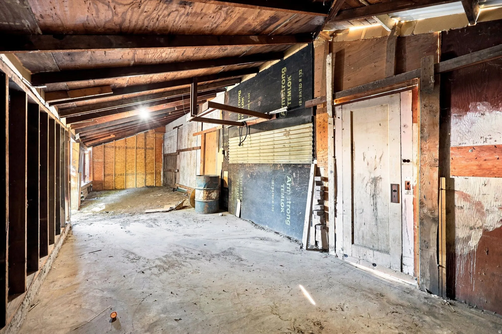 Exposed wood beam ceiling, concrete flooring, and unfinished wall studs