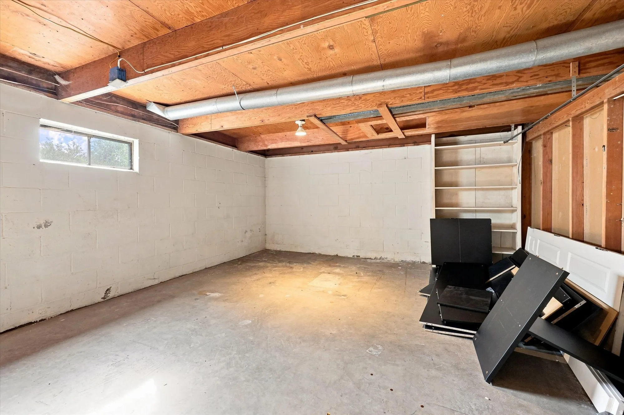 Concrete flooring with a single-pane window and exposed wooden ceiling beams