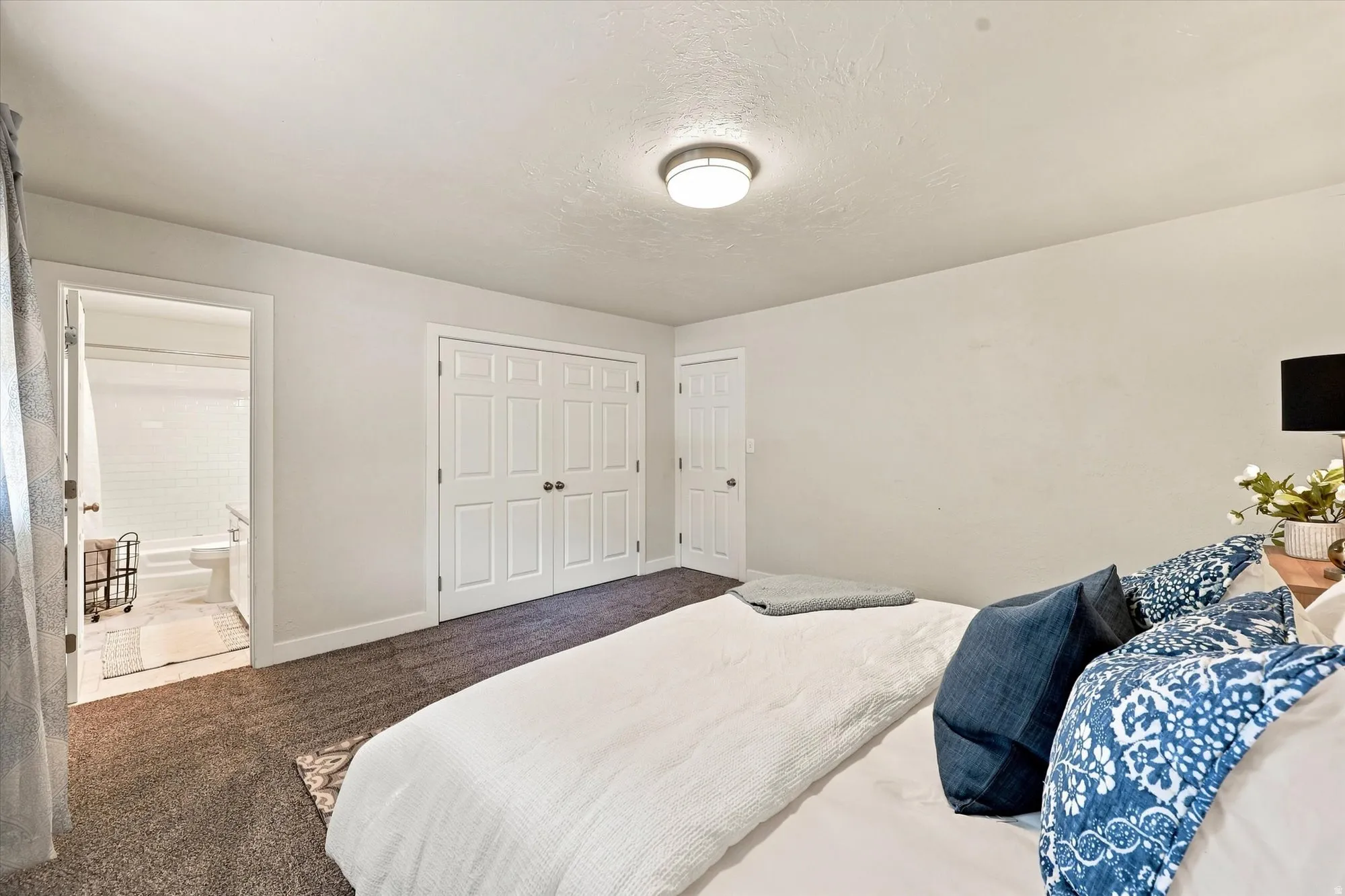 Plush carpet flooring, white painted walls, and a flush mount ceiling light fixture