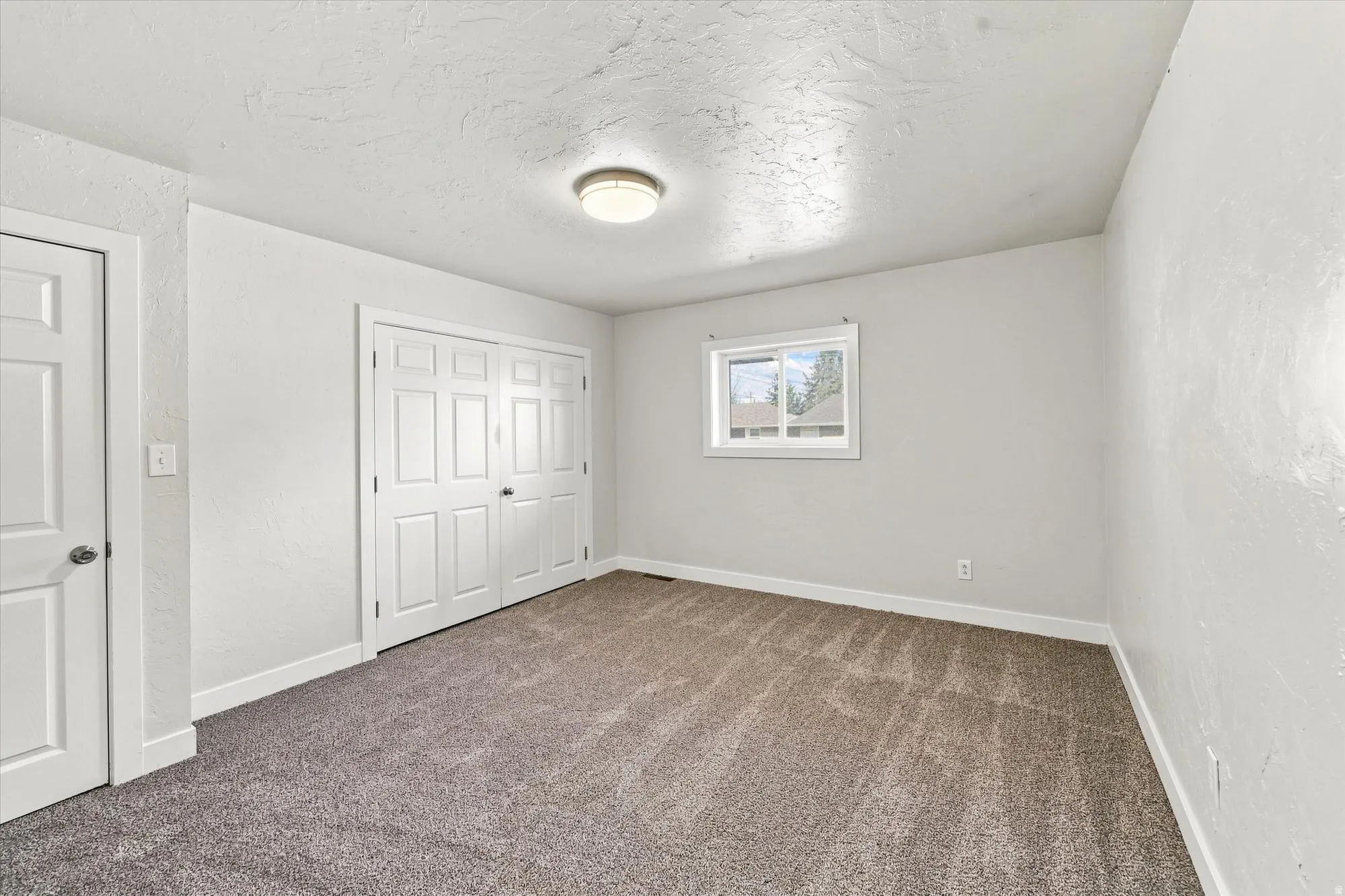 Neutral wall finishes, recessed window, flush-mount ceiling light, and bi-fold closet doors